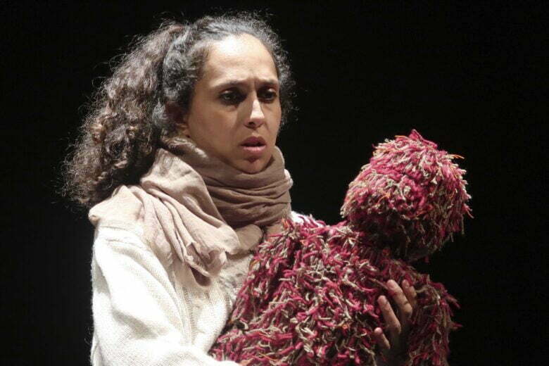 femme qui tient une peluche dans les mains alors qu'elle joue une pièce sur une scène